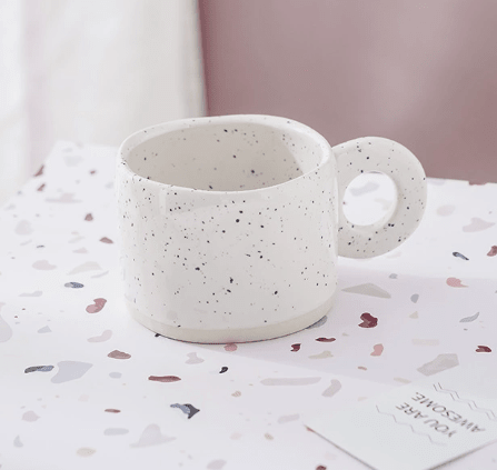 Lunar Clarity White porcelain tea cup with asymmetrical silhouette and cosmic ink-splash glaze by Recharge7.
